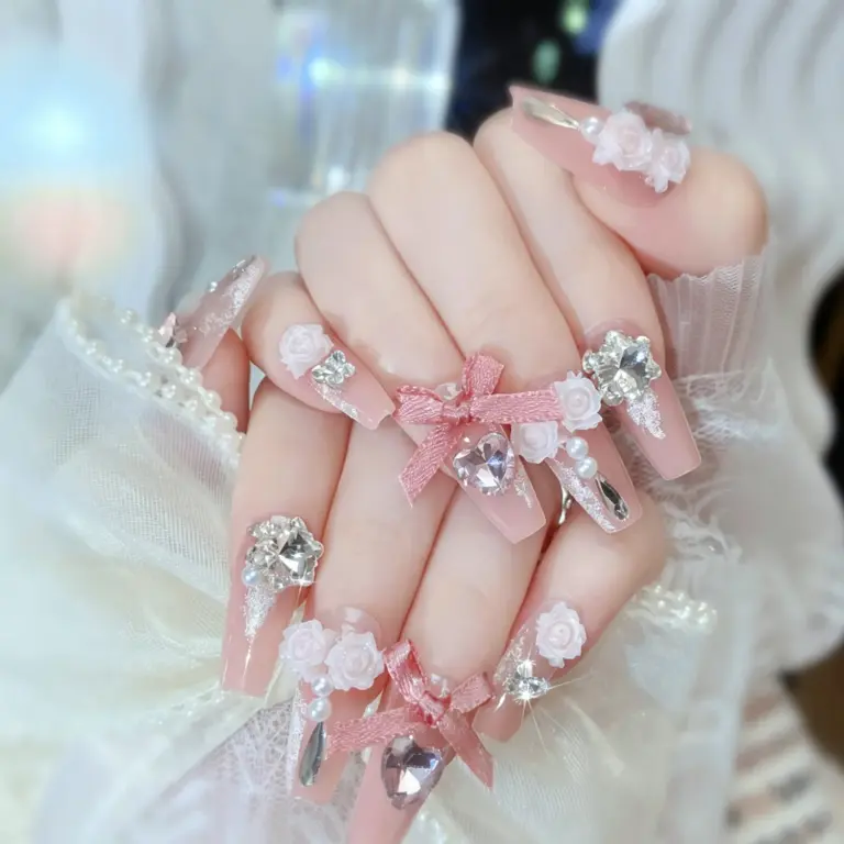 Close-up of romantic pink ombre rose bow crystal press-on nails on hand