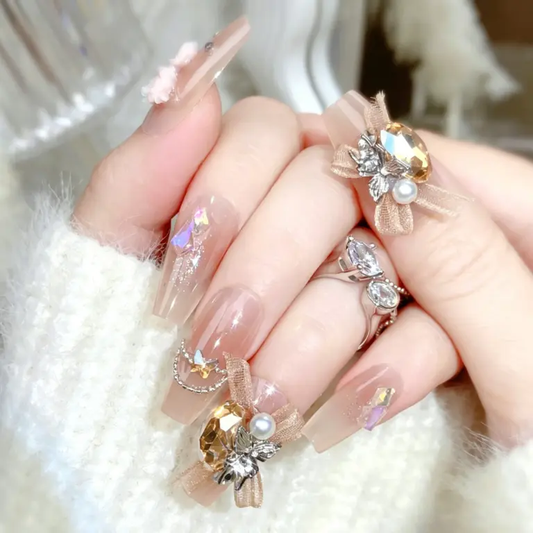 Close-up of champagne gradient press-on nails with roses and bows on hand