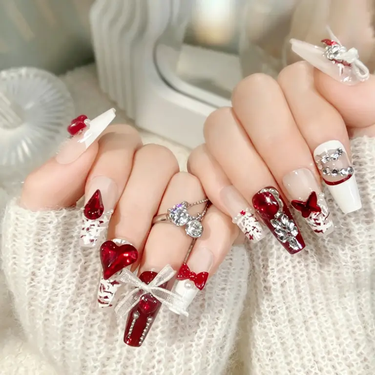 Close-up of red white heart bow press-on nails on hand