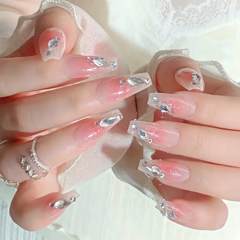 Close up of pink blush gradient rhinestone press on nails on a hand
