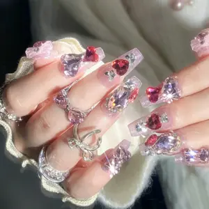 Close up of pink heart rhinestone press on nails on a hand