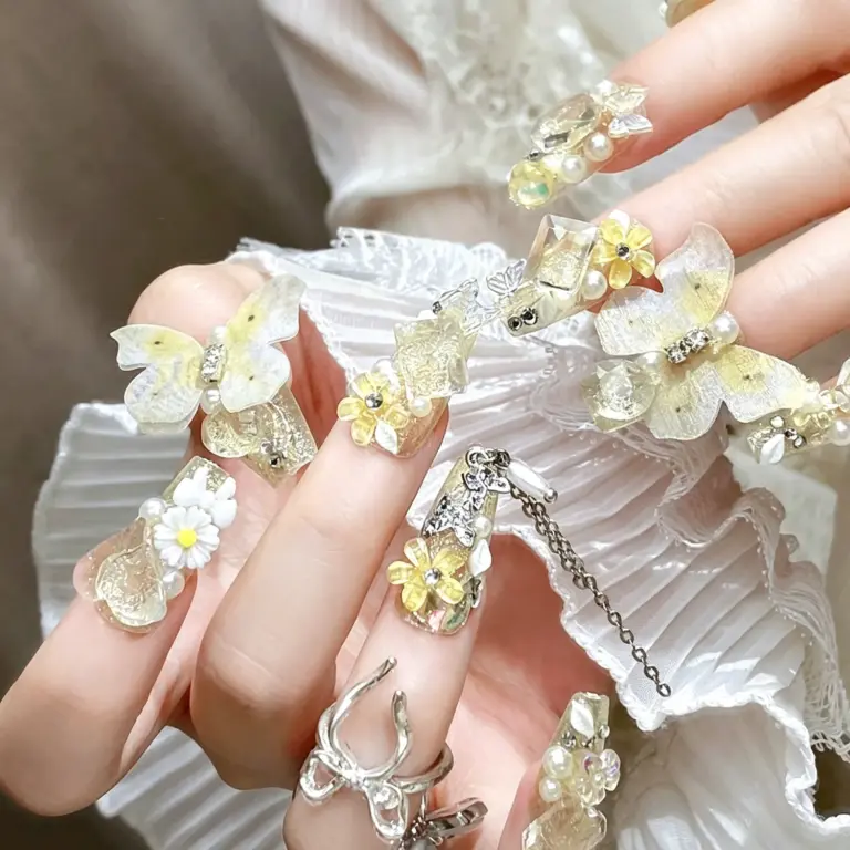 Close up of yellow butterfly daisy press on nails on hand